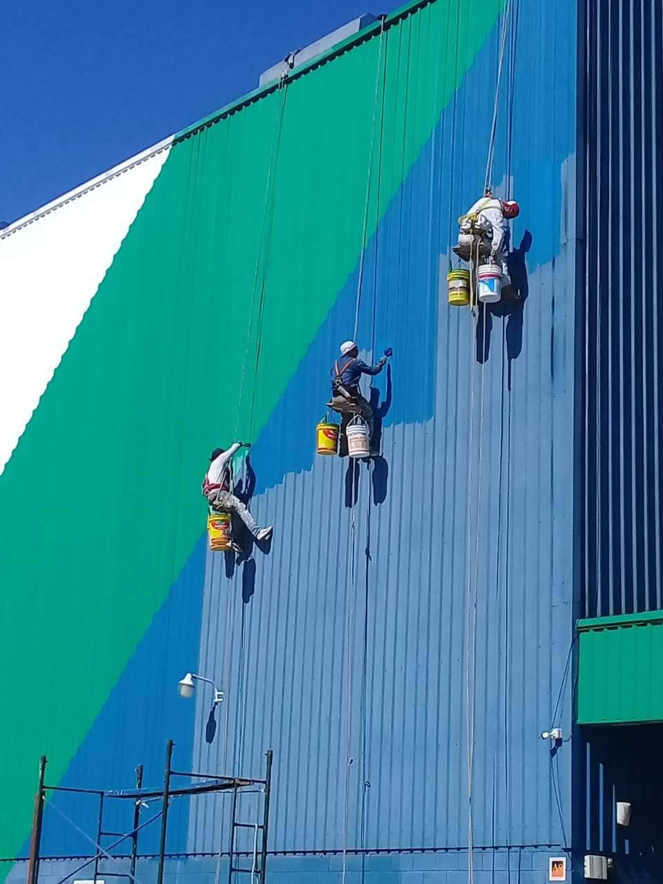 Equipo de Fachada Urbana trabajando suspendido sobre una medianera